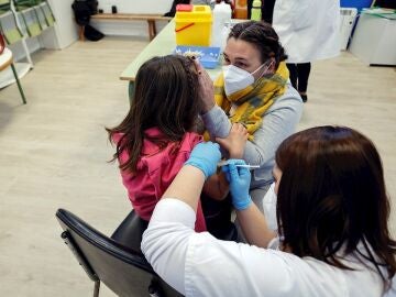 Una madre acompaña a su hija mientras la vacunan en el CEIP Blasco de Alagón de Vilafranca durante el inicio de la segunda fase de la campaña de vacunación pediátrica contra el coronavirus que comienza este jueves, centrada en los 186.088 niños y niñas de entre 8 y 5 años que estudian en los centros escolares de la Comunitat Valenciana.