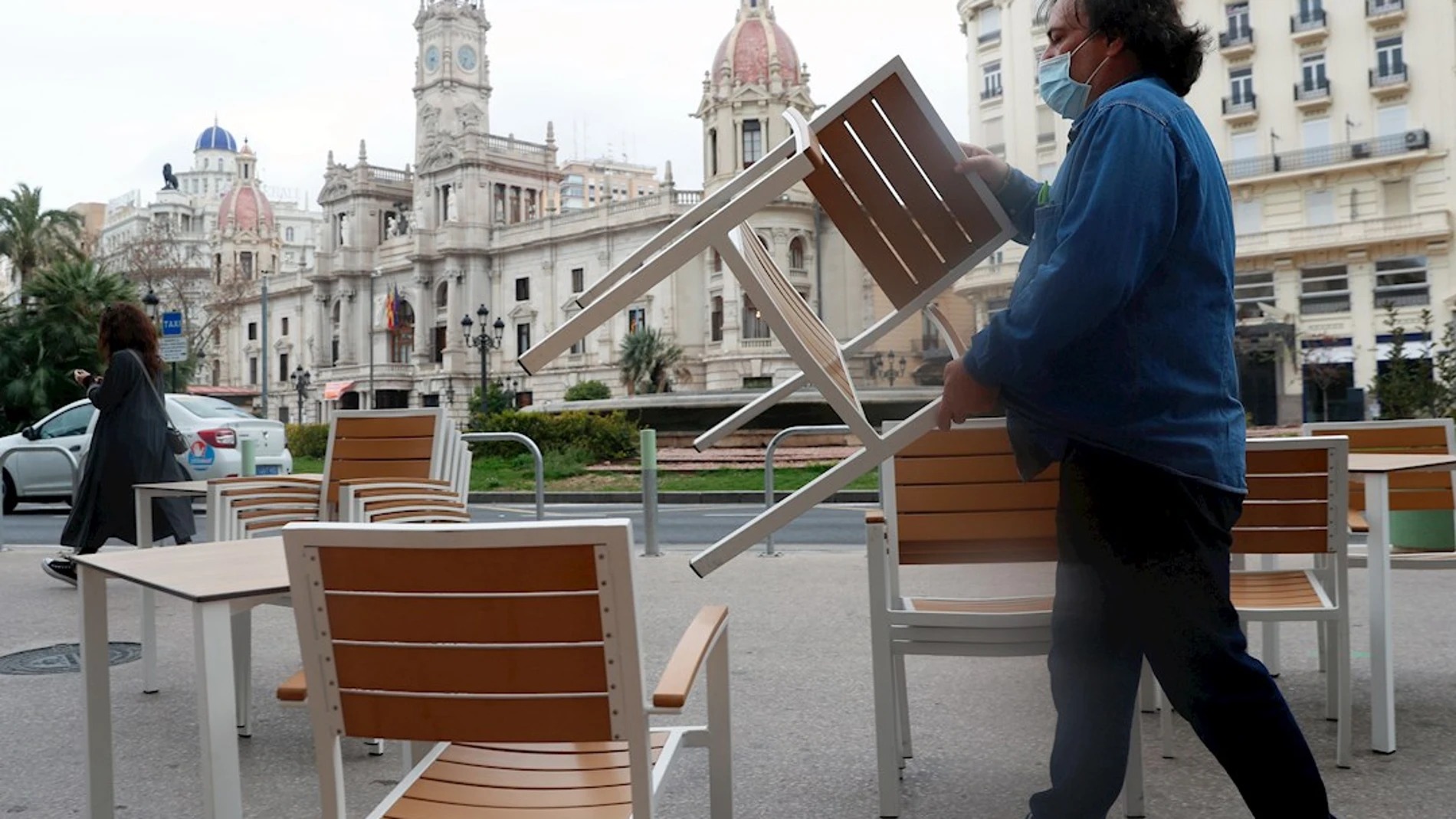 Un camarero coloca sillas y mesas en su local de la Plaza del Ayuntamiento de Valencia, en una fotografía de archivo