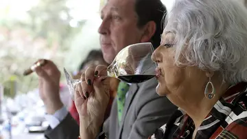 Una mujer bebe una copa de vino tinto, foto de archivo