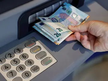 Una persona saca dinero de un cajero de una entidad bancaria, en una imagen de archivo