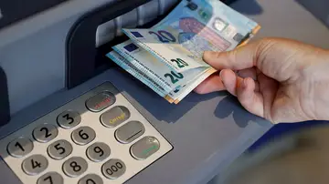 Una persona saca dinero de un cajero de una entidad bancaria, en una imagen de archivo