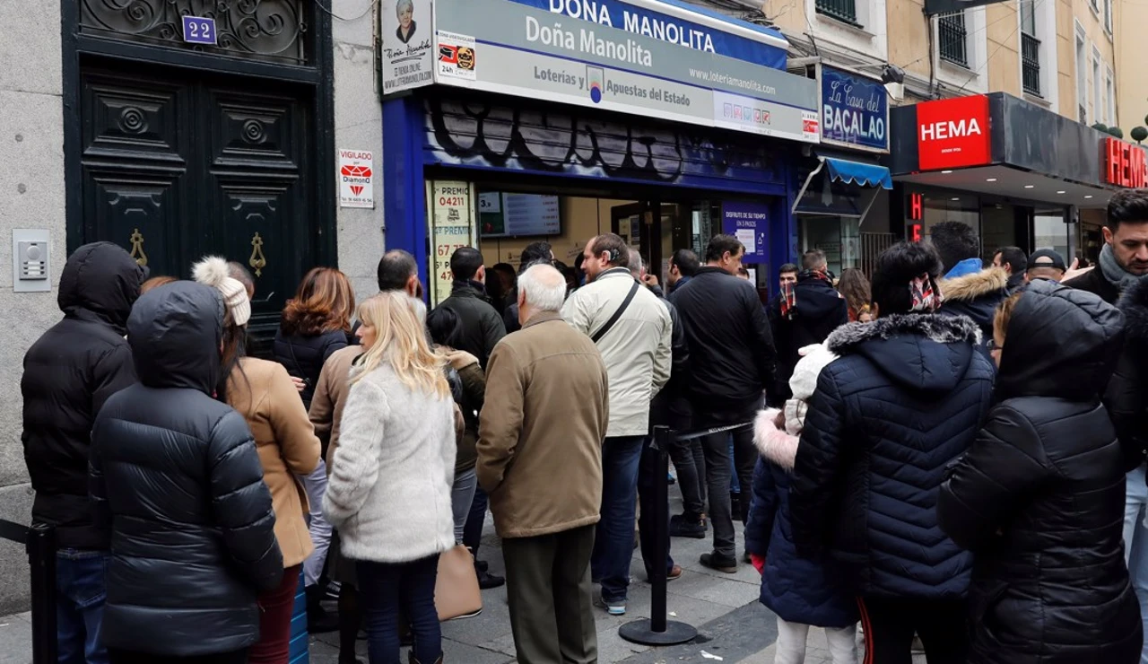 Varias personas hacen cola frente a la administración de lotería Doña Manolita, en Madrid