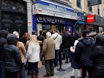 Varias personas hacen cola frente a la administración de lotería Doña Manolita, en Madrid