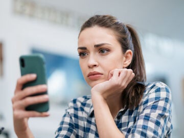 Una joven mira el móvil con preocupación