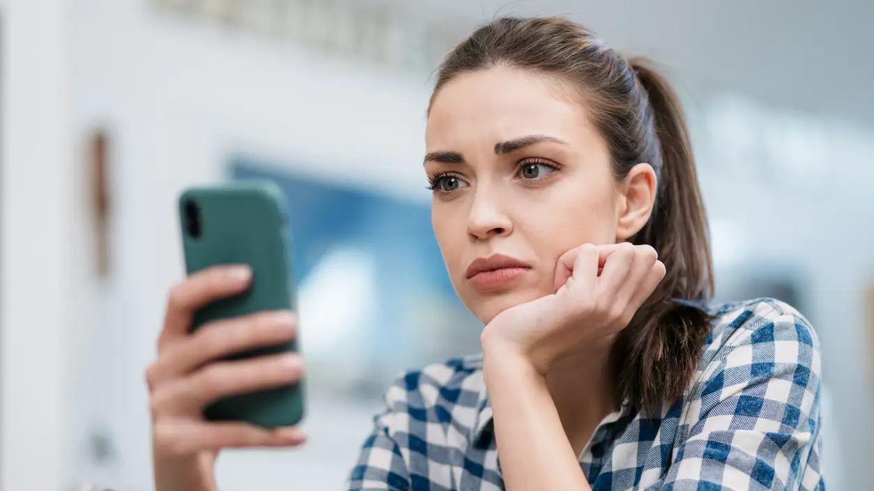 Una joven mira el m&oacute;vil con preocupaci&oacute;n