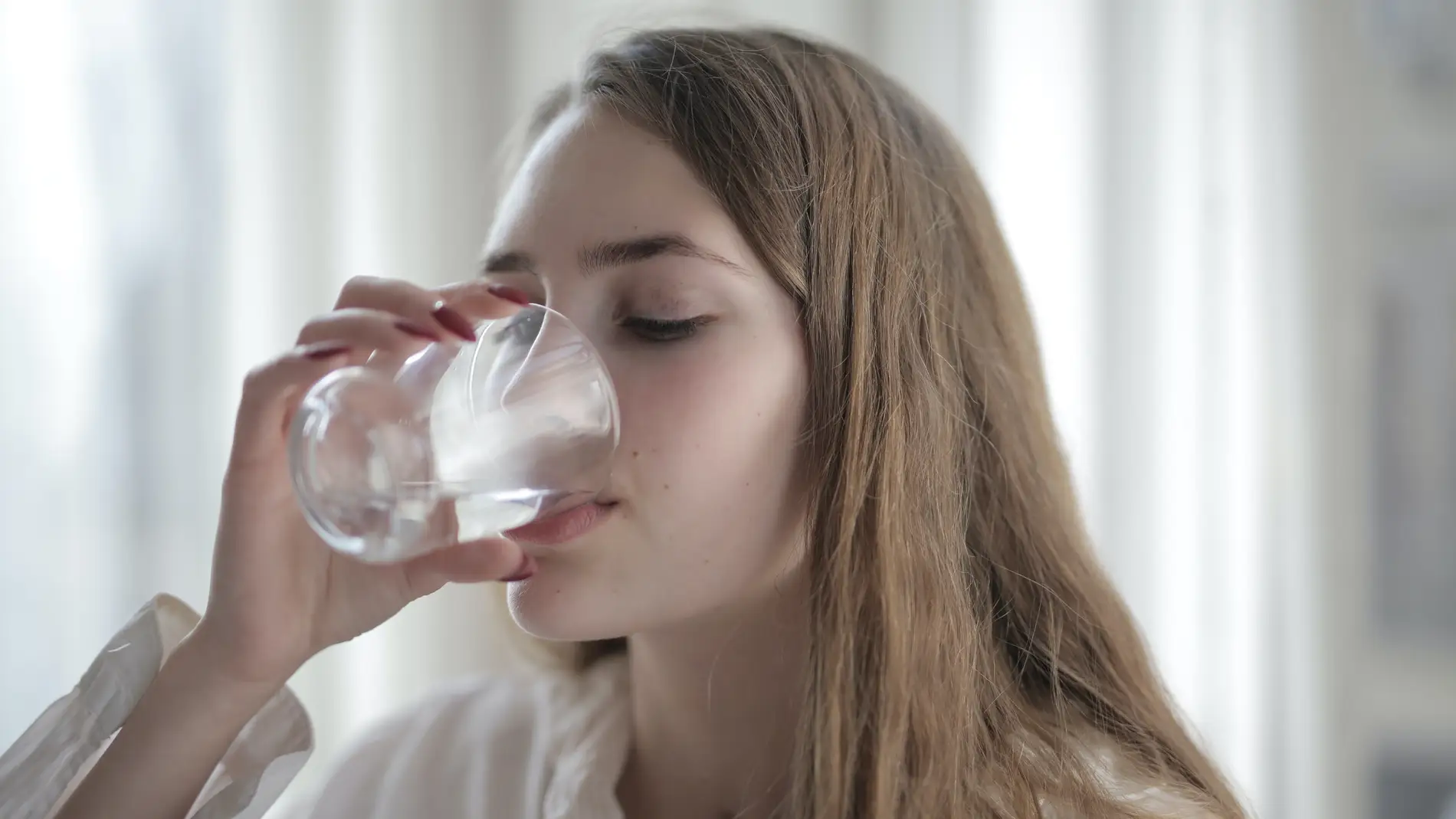 Mujer bebiendo un vaso de agua.
