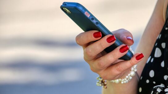 Una mujer sostiene un tel&eacute;fono m&oacute;vil