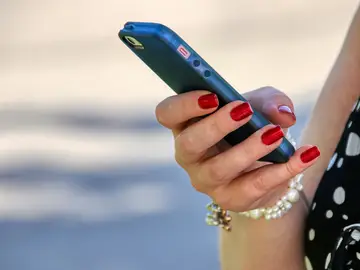 Una mujer sostiene un teléfono móvil Una mujer sostiene un teléfono móvil