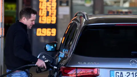 Una persona repostando en una gasolinera Una persona repostando en una gasolinera