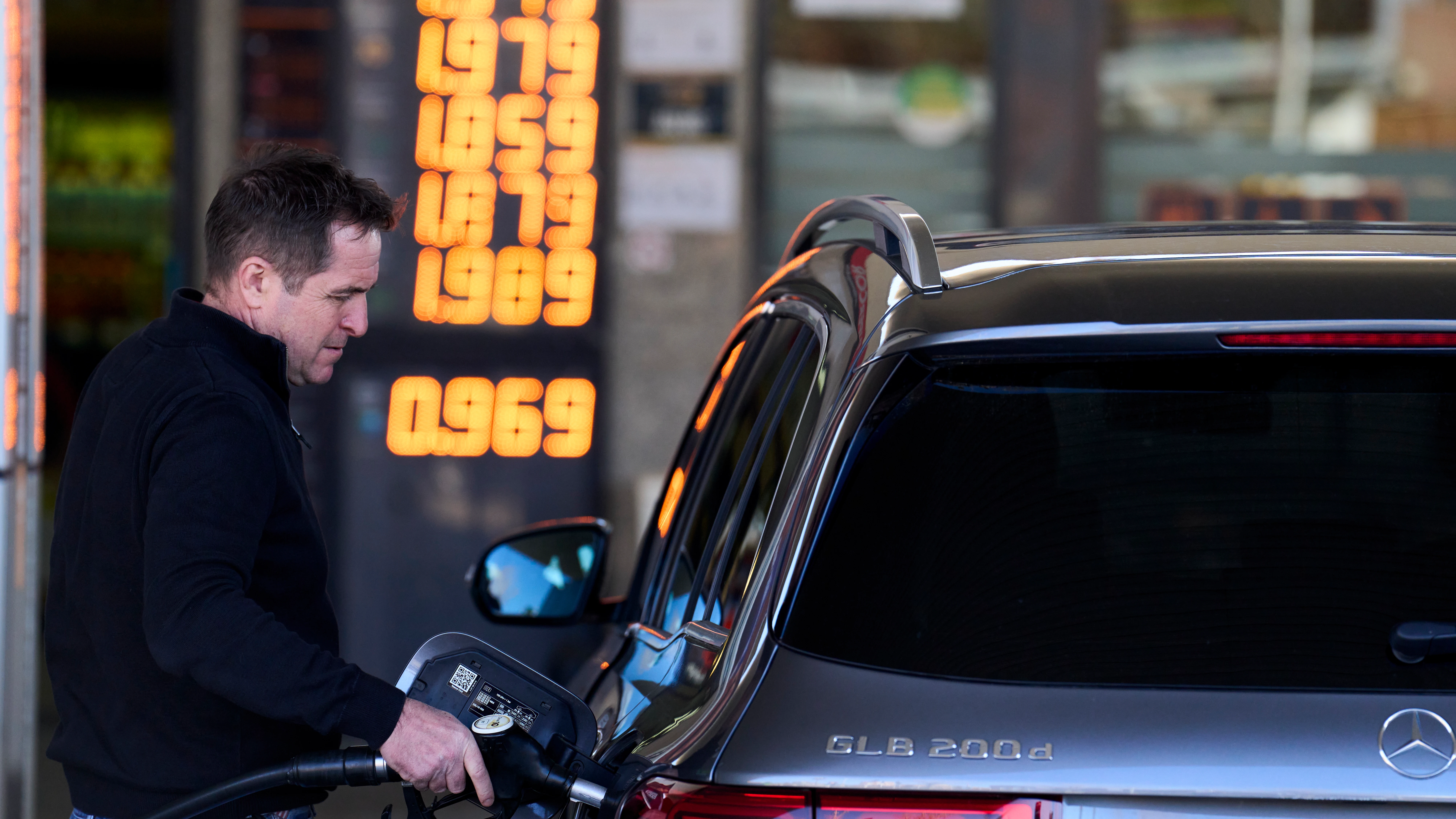 Una persona repostando en una gasolinera Una persona repostando en una gasolinera