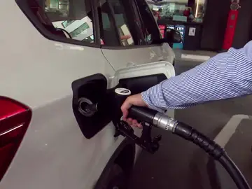 Una persona echa combustible en una gasolinera Una persona echa combustible en una gasolinera