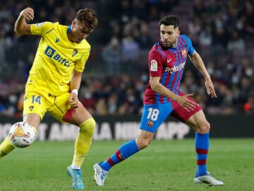 El delantero del Cádiz, Iván Alejo (i), intenta controlar el balón ante el defensa del FC Barcelona, Jordi Alba, durante el encuentro correspondiente a la jornada 32 de primera división disputado hoy lunes en el estadio del Camp Nou