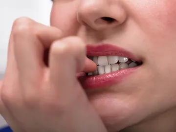 Persona mordiéndose las uñas. Persona mordiéndose las uñas.