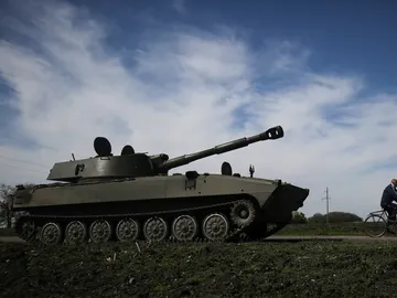 Un hombre pasea en bicicleta al lado de un tanque en la localidad ucrania de Jarkov Un hombre pasea en bicicleta al lado de un tanque en la localidad ucrania de Jarkov