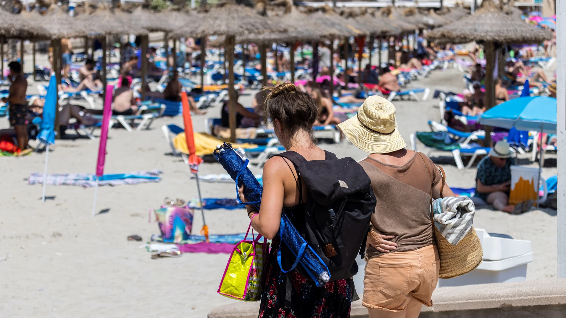 Turistas disfrutan del sol en la playa de Peguera