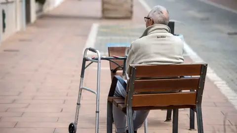 Una persona mayor sentada en un banco Una persona mayor sentada en un banco