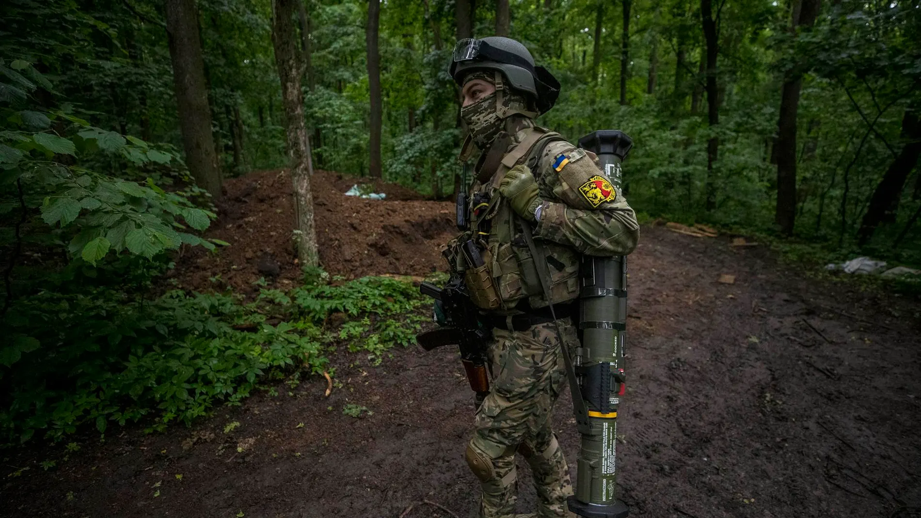 Un soldado carga con un lanzagranadas cerca de una trinchera en medio de un bosque en Ucrania
