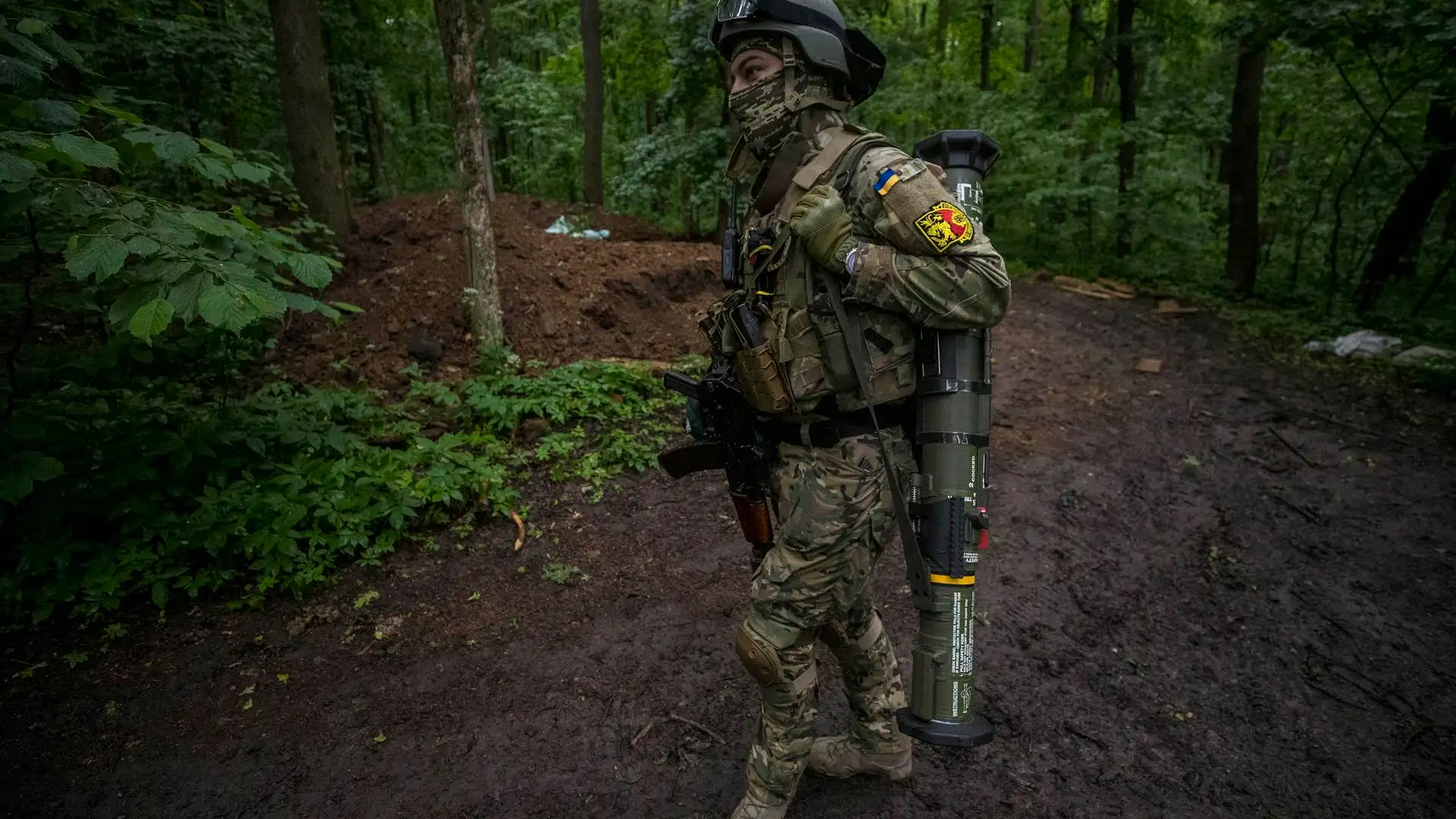 Un soldado carga con un lanzagranadas cerca de una trinchera en medio de un bosque en Ucrania Un soldado carga con un lanzagranadas cerca de una trinchera en medio de un bosque en Ucrania