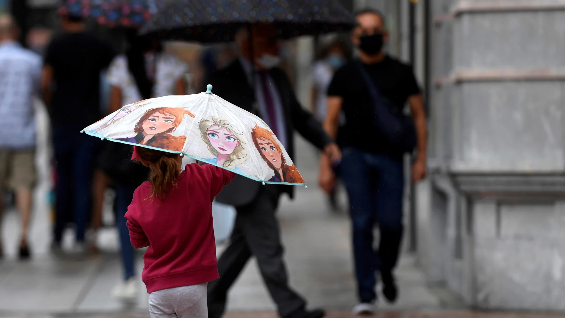 En la imagen de archivo, una niña se protege de la lluvia en Oviedo