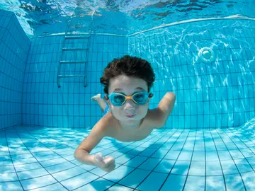 Un niño con gafas de bucear en una piscina Un niño con gafas de bucear en una piscina