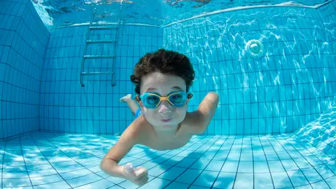 Un niño con gafas de bucear en una piscina Un niño con gafas de bucear en una piscina