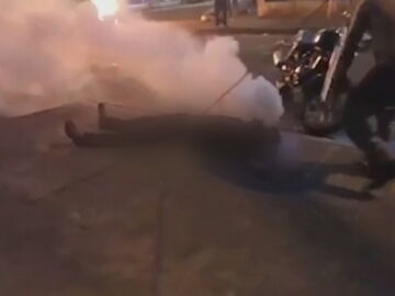 El joven rodeado de humo tras el impacto de la botella de gas lacrimógeno