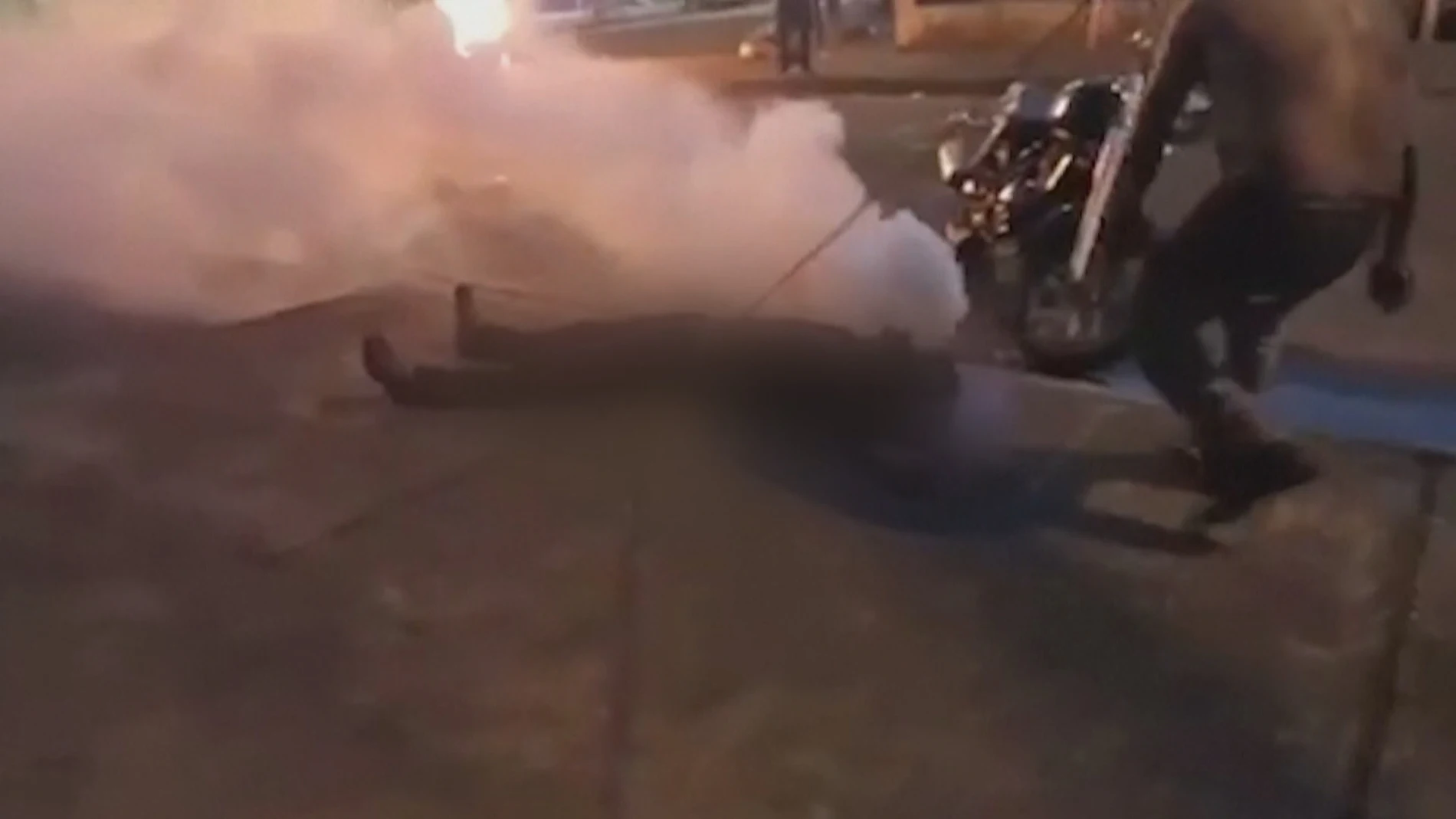 El joven rodeado de humo tras el impacto de la botella de gas lacrimógeno