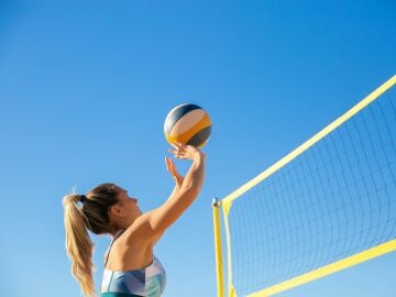 Una chica juega a voleibol en la playa.