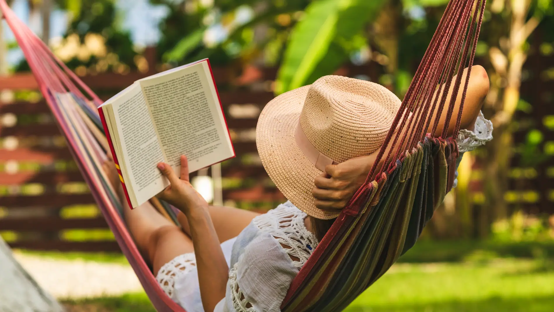 Una chica disfruta leyendo en una hamaca.