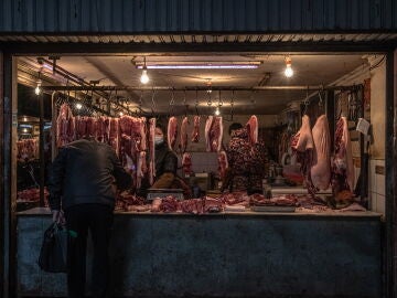 Una mujer vende carne en un mercado de un área residencial de Wuhan