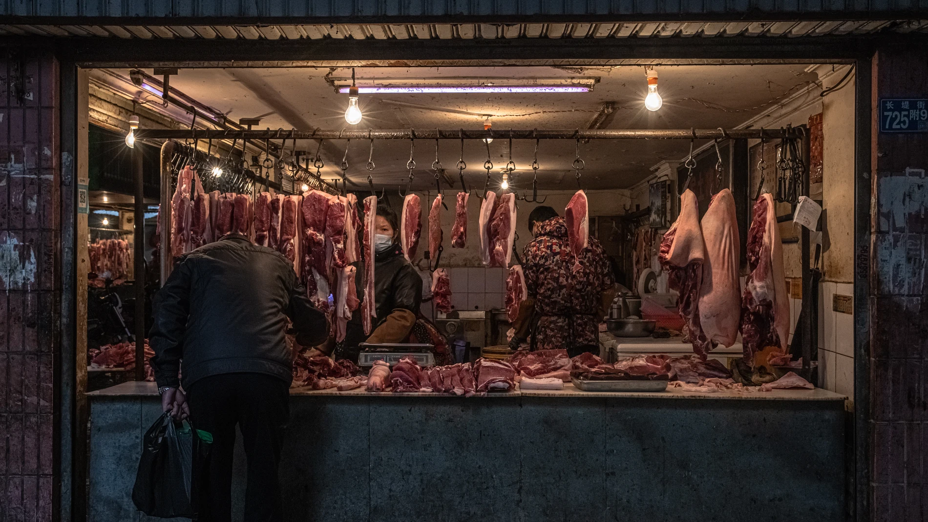 Una mujer vende carne en un mercado de un área residencial de Wuhan