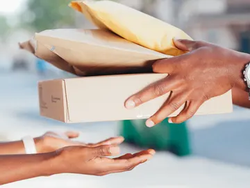 Persona entregando paquetes a otra persona Persona entregando paquetes a otra persona