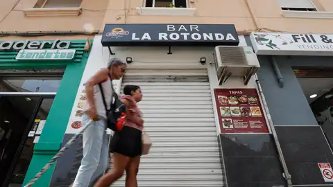 Dos mujeres pasan por delante de la persiana del bar, en Valencia Dos mujeres pasan por delante de la persiana del bar, en Valencia