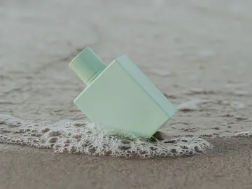 Frasco de perfume en la arena de la playa Frasco de perfume en la arena de la playa