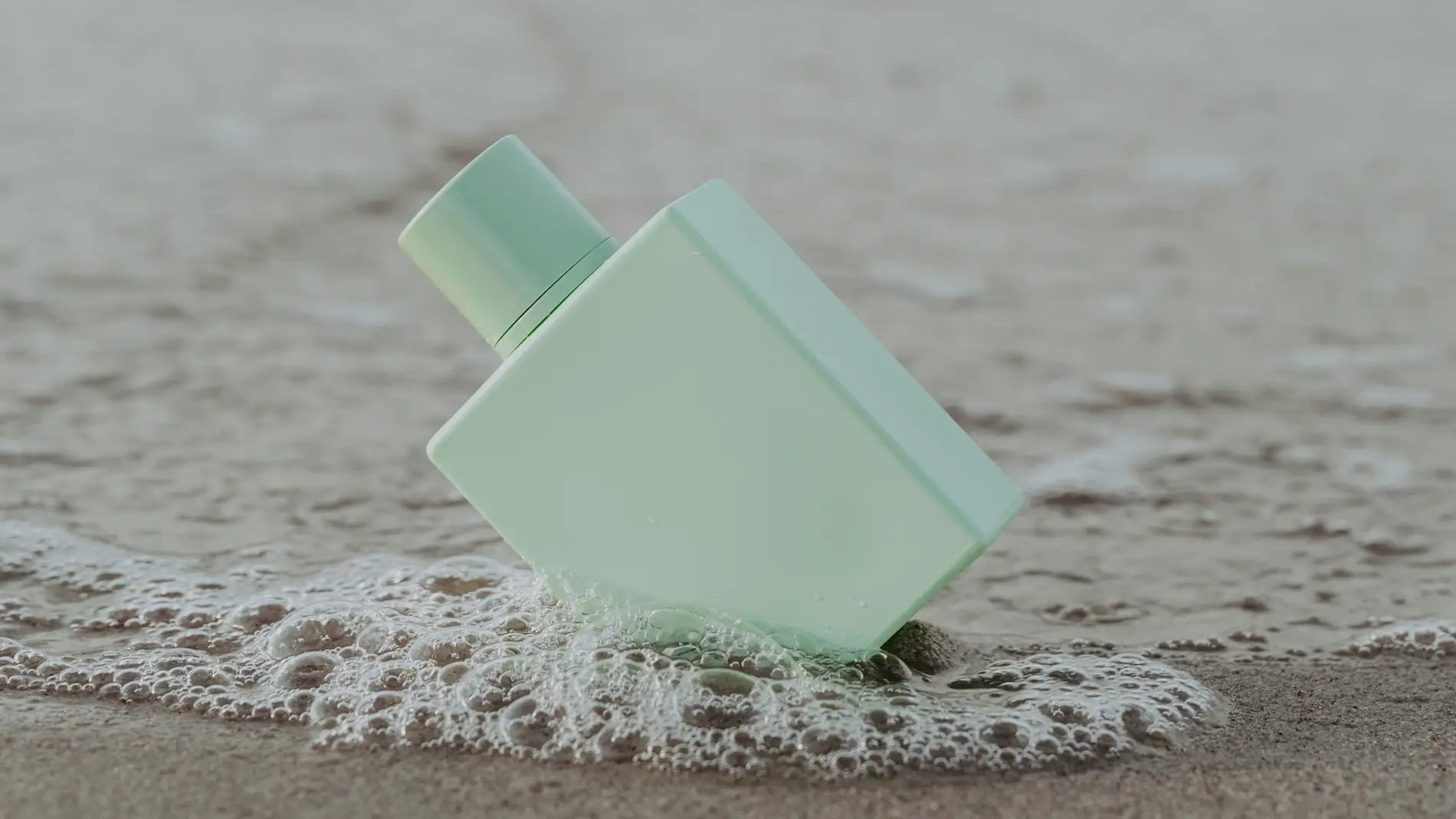 Frasco de perfume en la arena de la playa