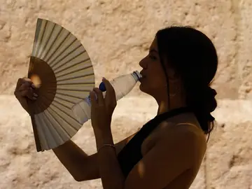 Mujer bebiendo agua sofocada por el calor Mujer bebiendo agua sofocada por el calor