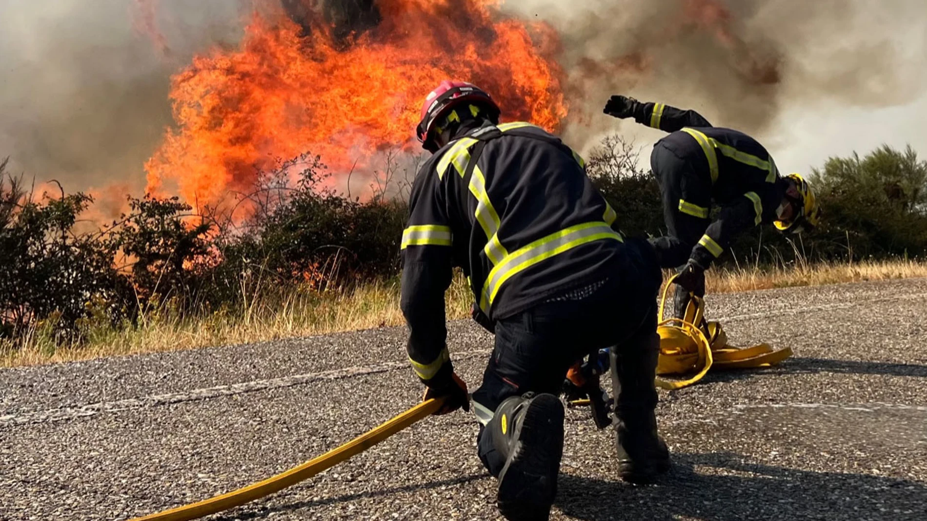 Efectivos de bomberos trabajan este domingo en la extinción de un incendio forestal en la carretera N120, actualmente cortada por las llamas, en A Cañiza (Pontevedra)