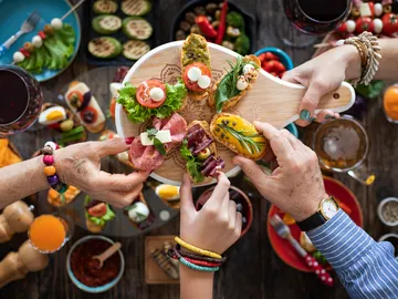 Un grupo de personas comparte comida de una bandeja. Un grupo de personas comparte comida de una bandeja.