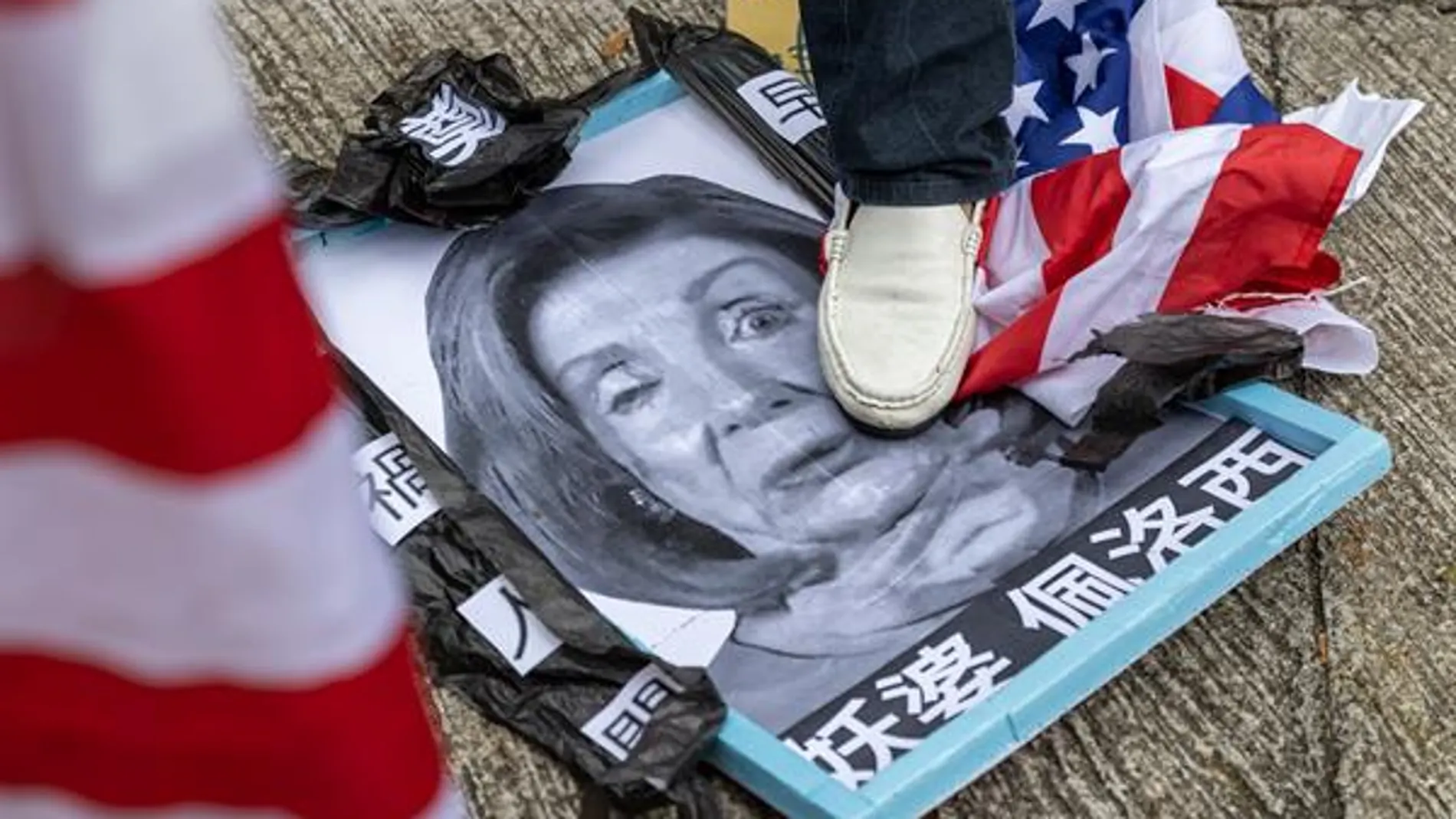 Una manifestante a favor de China pisotea un cartel con la cara de Nancy Pelosi en Hong Kong