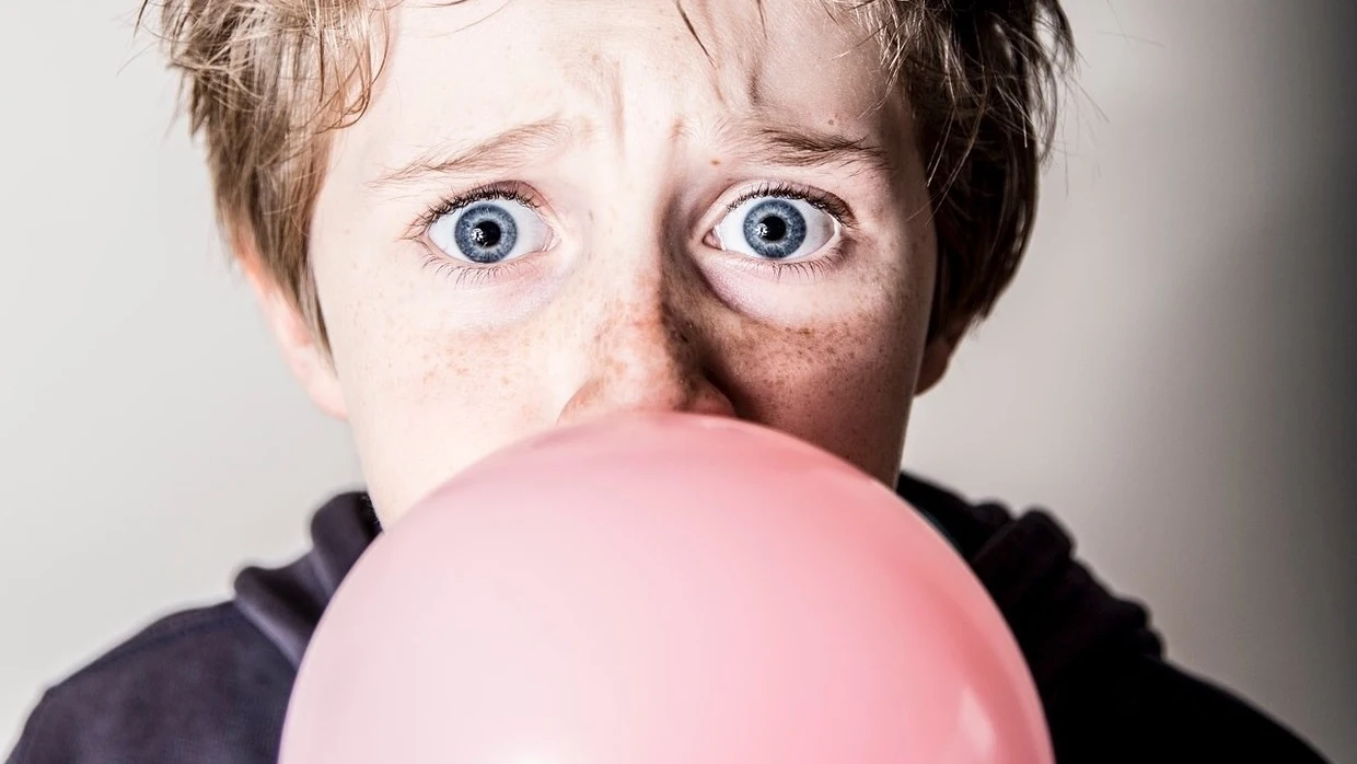 Niño haciendo una pompa con el chicle Niño haciendo una pompa con el chicle
