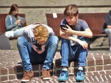 Dos adolescentes comunicándose a través del teléfono móvil.