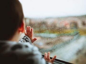 Un niño mira la lluvia por la ventana