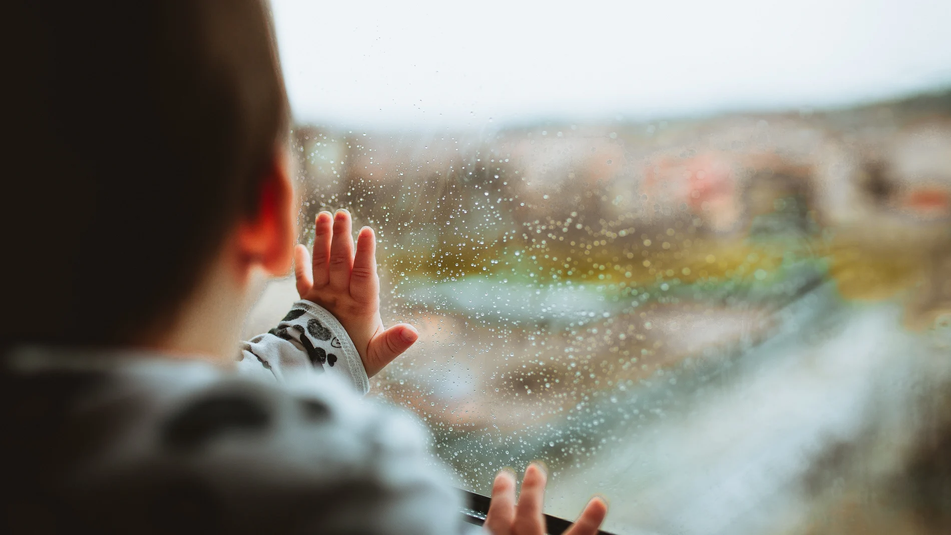 Un niño mira la lluvia por la ventana