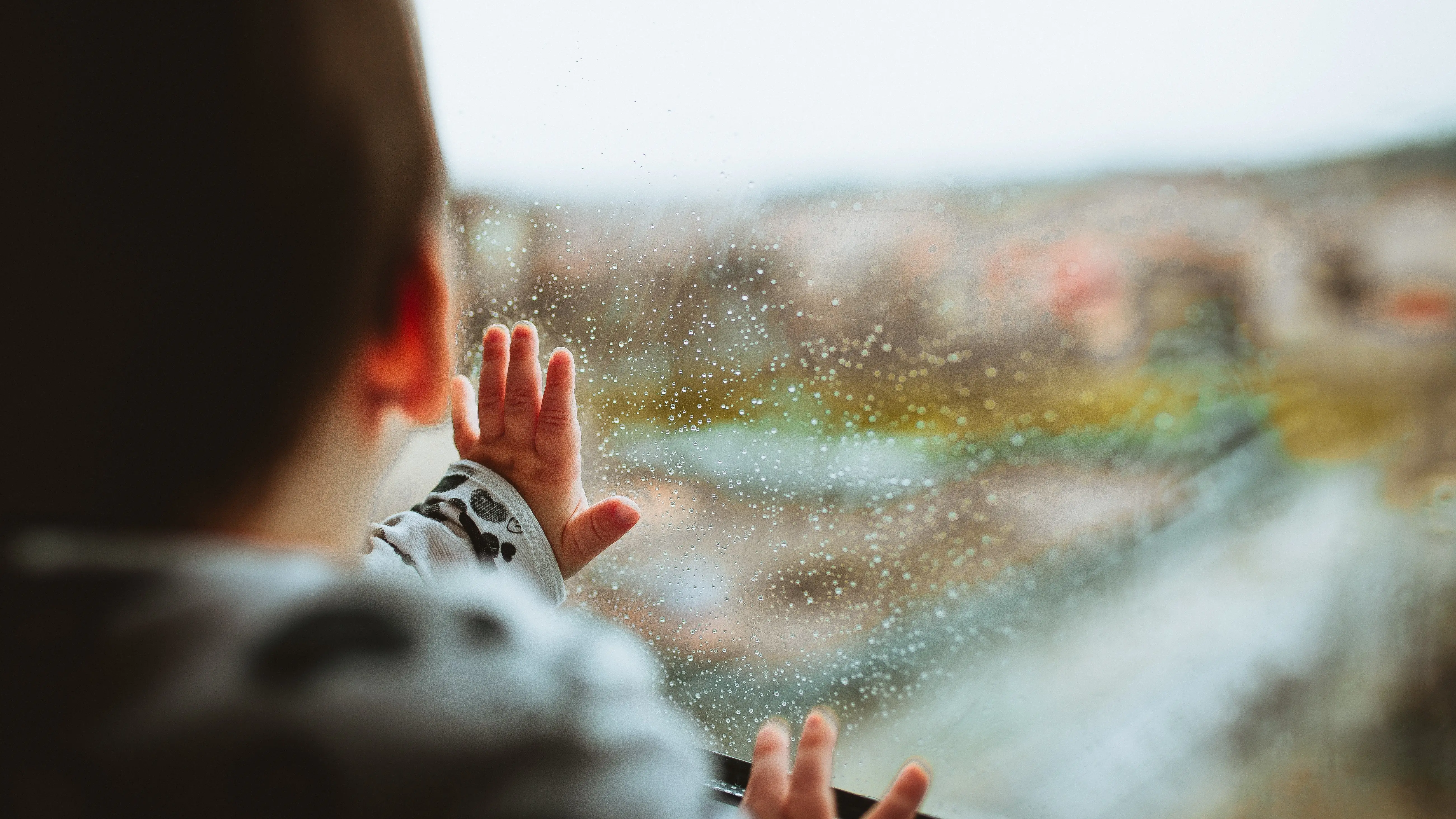 Un ni&ntilde;o mira la lluvia por la ventana