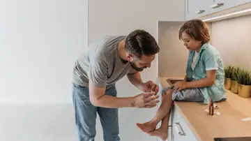 Adulto curando en casa la herida de la rodilla de un niño