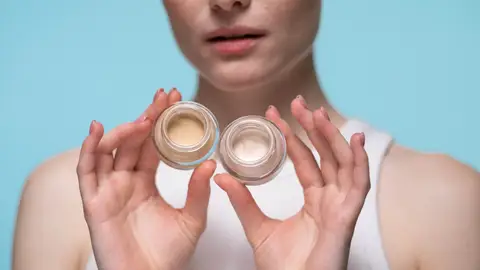 Primer plano de mujer con dos frascos de corrector Primer plano de mujer con dos frascos de corrector