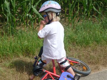 El niño estaba jugando con su bicicleta en el patio de la casa