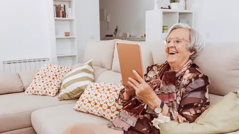 Día de las Personas Mayores: Una anciana disfruta consultando en la tablet Día de las Personas Mayores: Una anciana disfruta consultando en la tablet