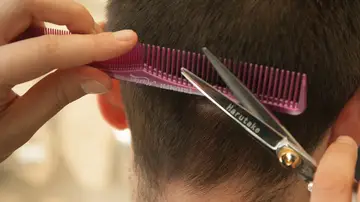 Un peluquero corta el pelo a un joven