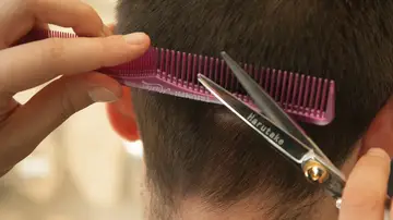 Un peluquero corta el pelo a un joven Un peluquero corta el pelo a un joven